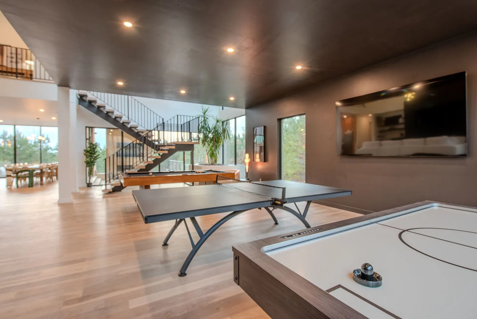 Lower-level recreation space at The Jade with air hockey table, modern spiral staircase, and recessed lighting