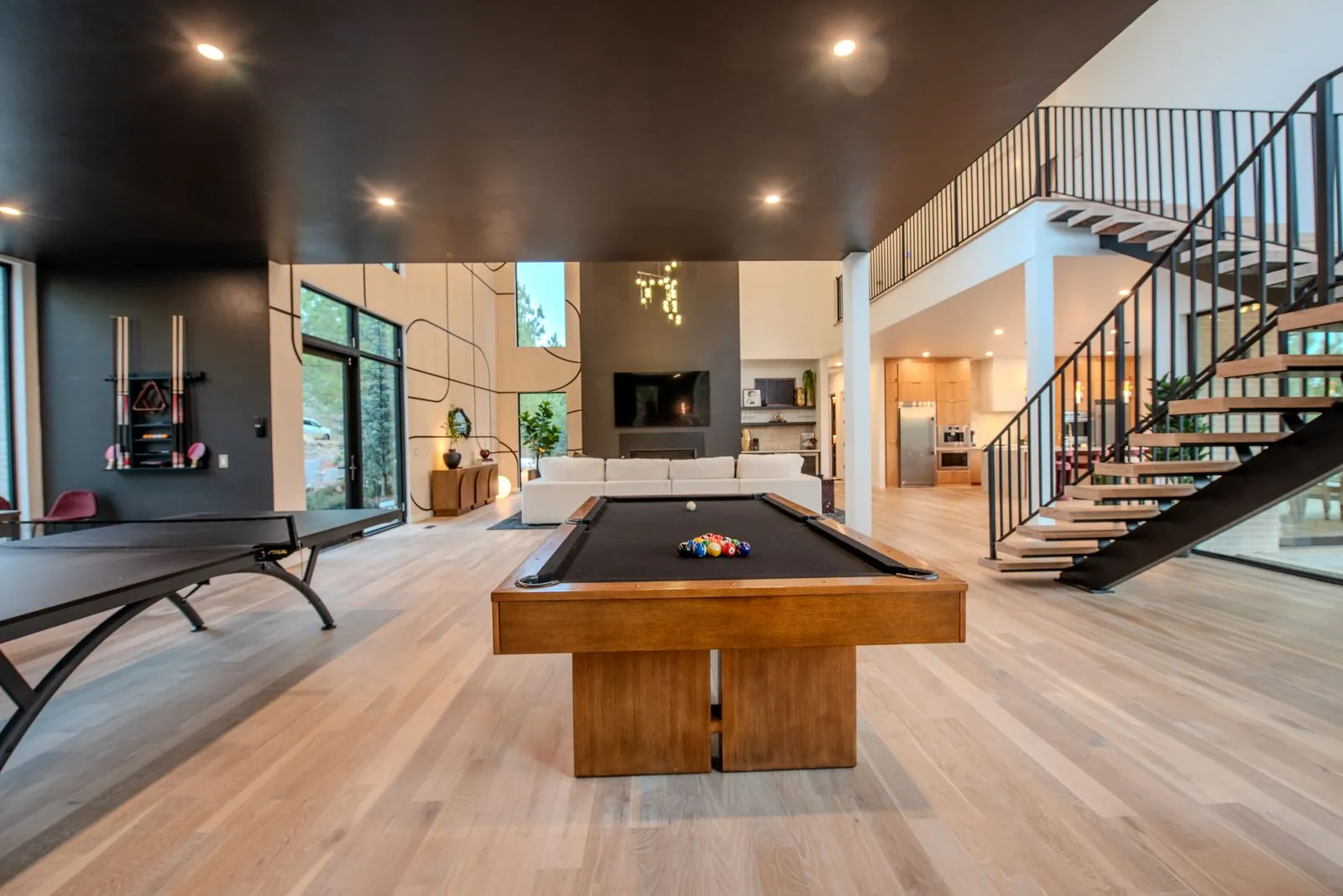 Billiard room at The Jade with pool table positioned beneath modern pendant lighting and open two-story layout