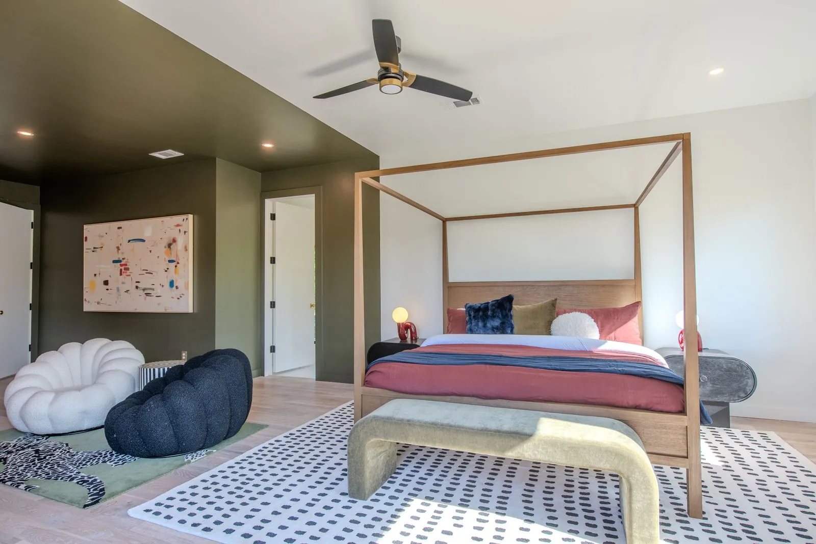 Primary bedroom at The Jade with canopy bed frame, geometric patterned floor, modern nightstands, and natural light