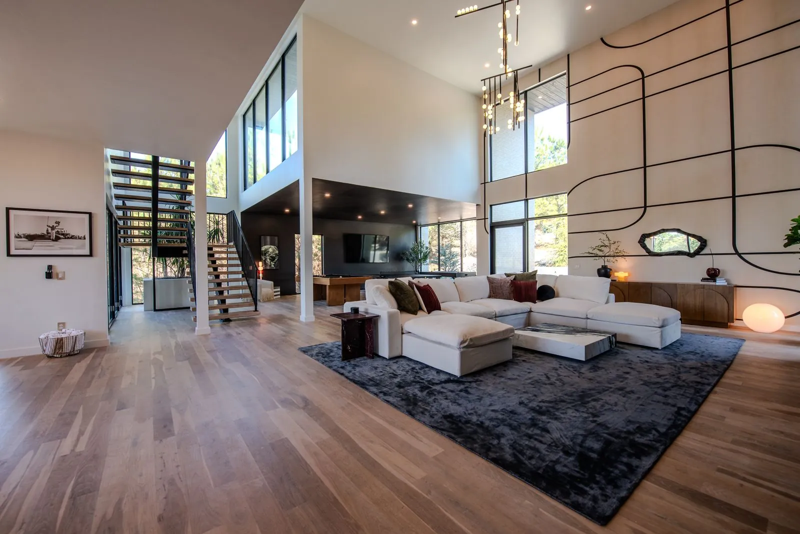 Upper-level view of The Jade open-concept living area showing white sectional sofa, spiral staircase, and double-height ceilings