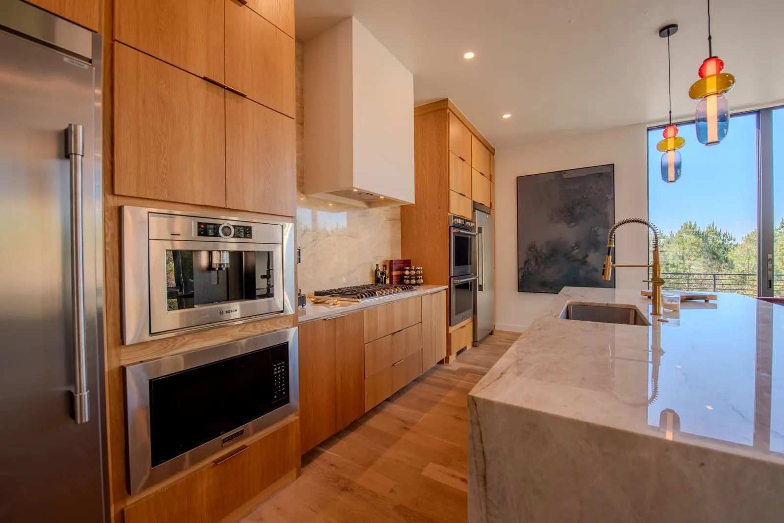 Built-in kitchen station at The Jade with double wall ovens, espresso machine, and warm wood cabinet surround