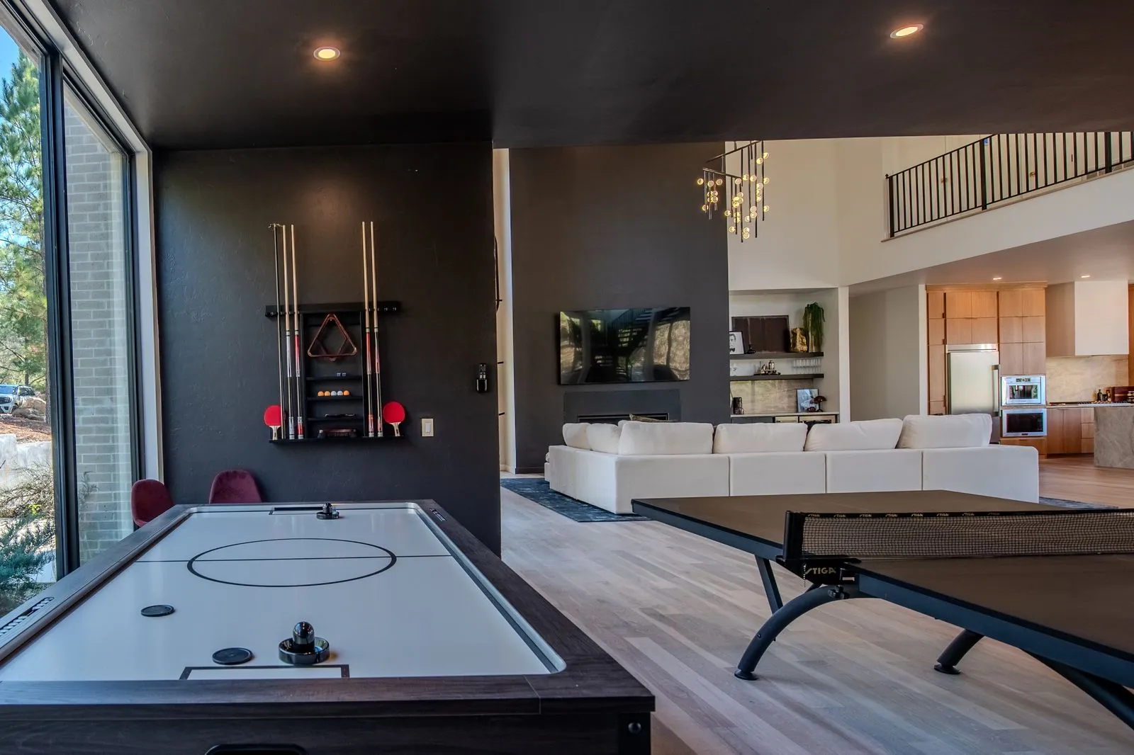 Open floor plan at The Jade looking from living area toward kitchen with air hockey table and natural hardwood floors