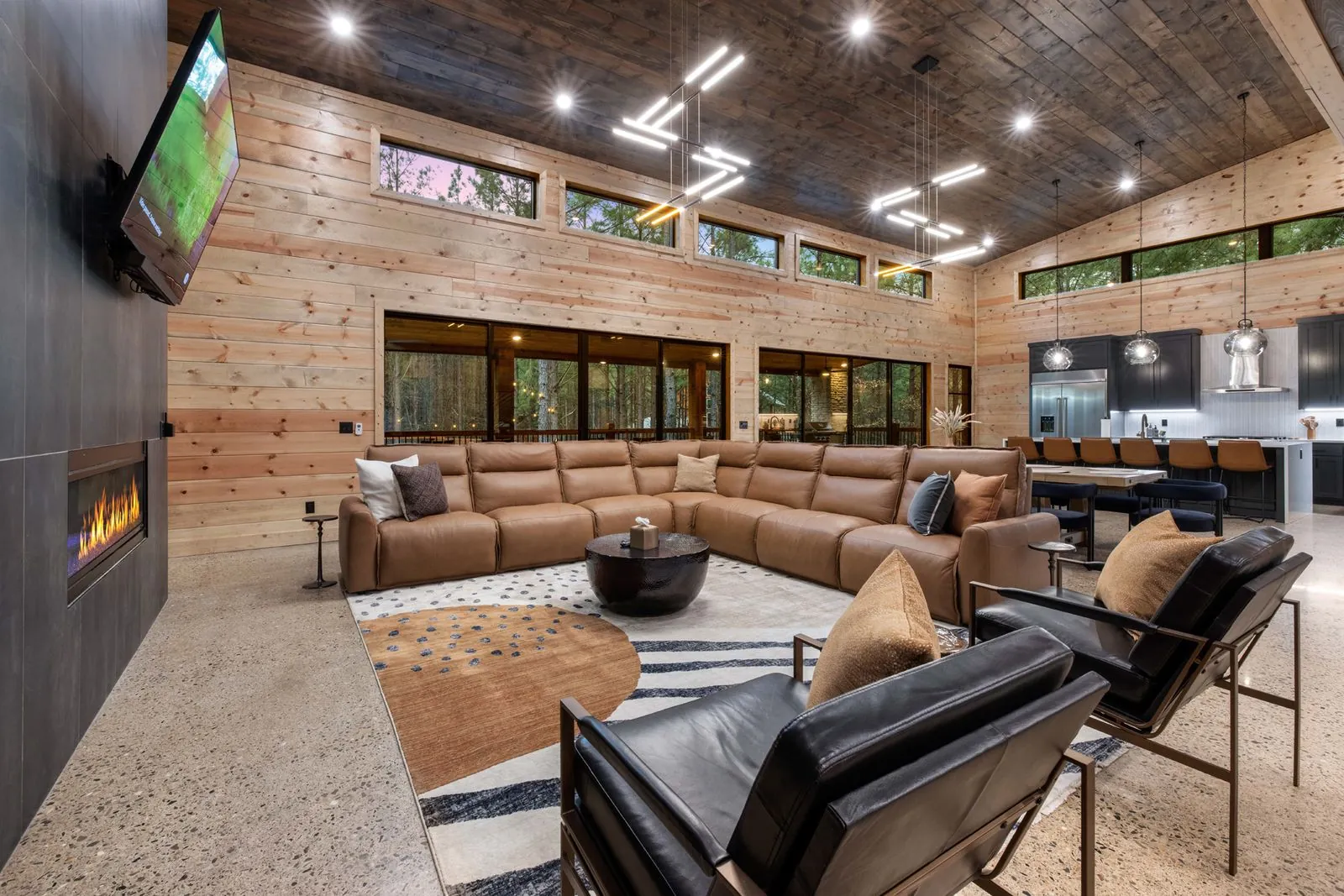 Living room at LivNLove with leather sectional, fireplace entertainment wall, and upper loft mezzanine