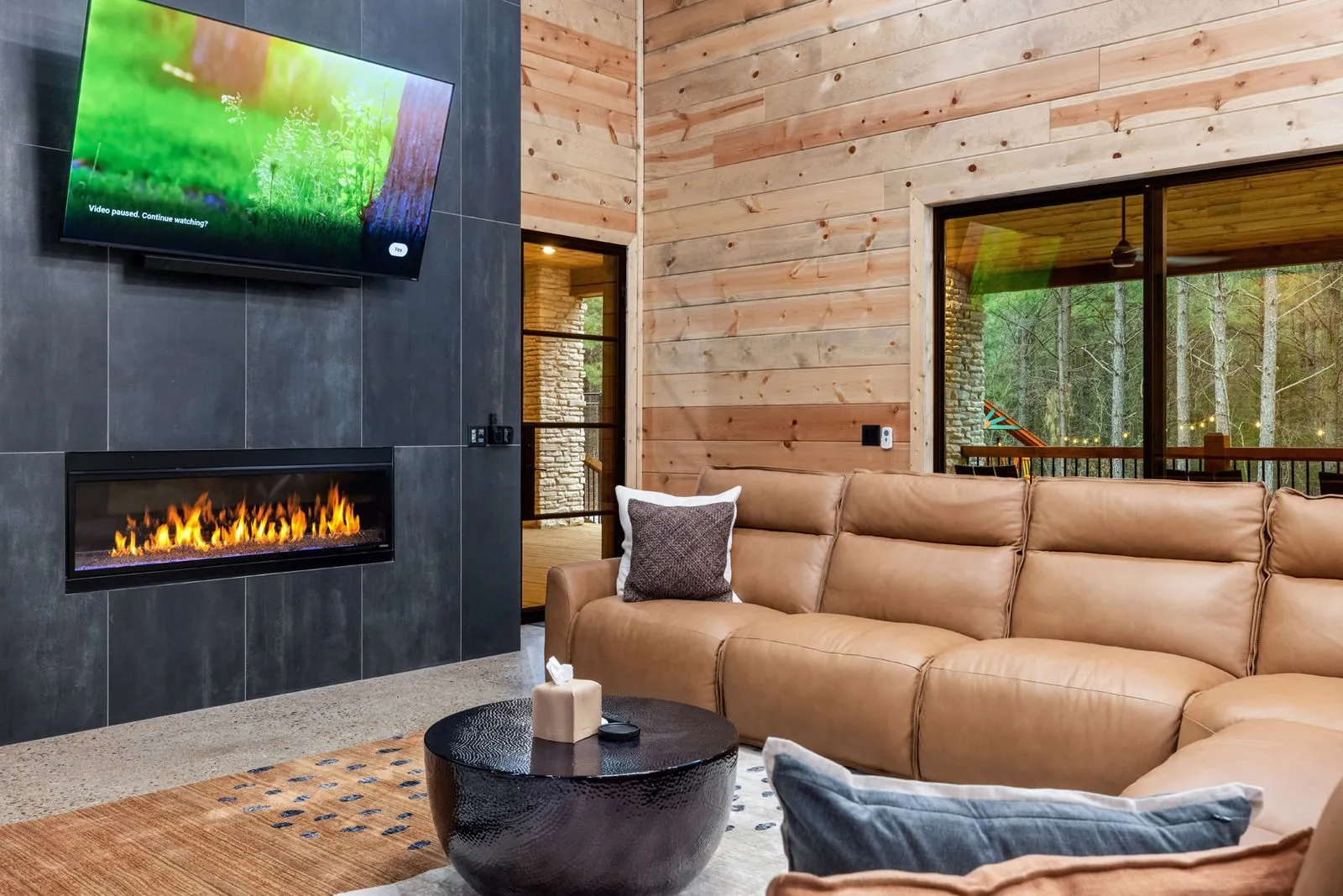 Wall-mounted TV above linear gas fireplace at LivNLove with dark charcoal and wood accent wall