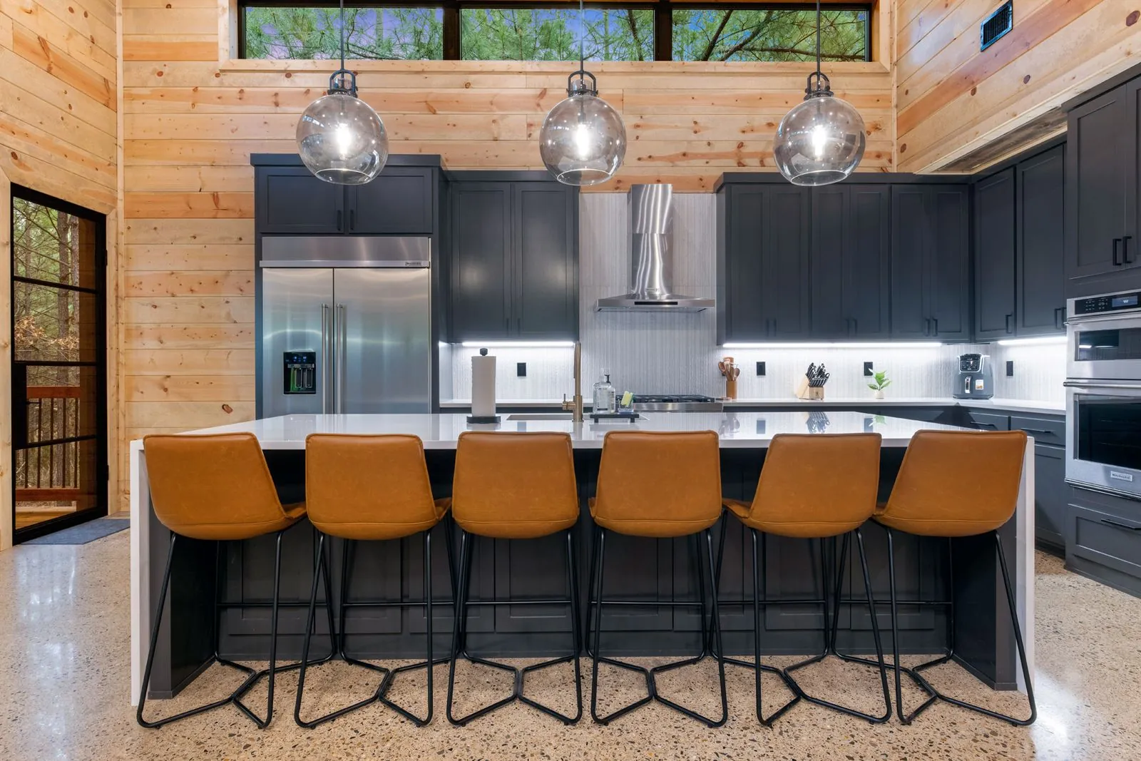Dining area at LivNLove showing table with navy chairs and open view to kitchen island with bar stools