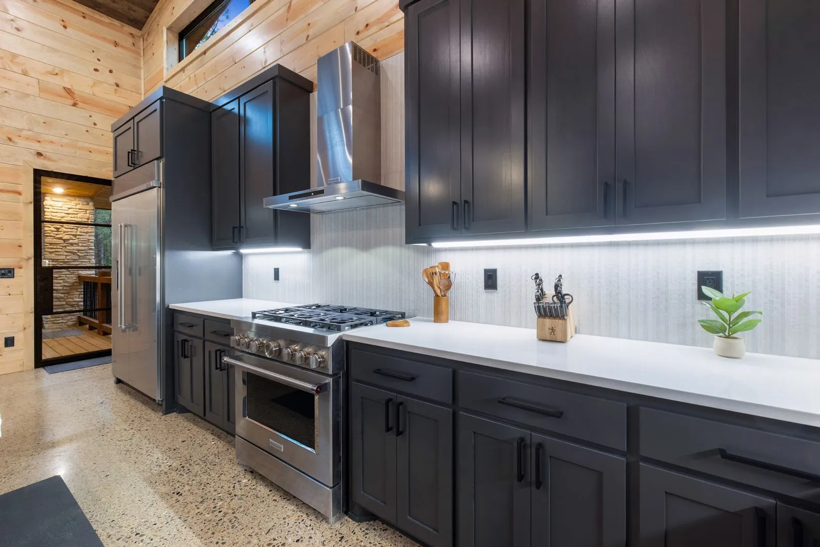 Kitchen island at LivNLove with tan leather stools, dark cabinetry, and artisan globe pendant lights