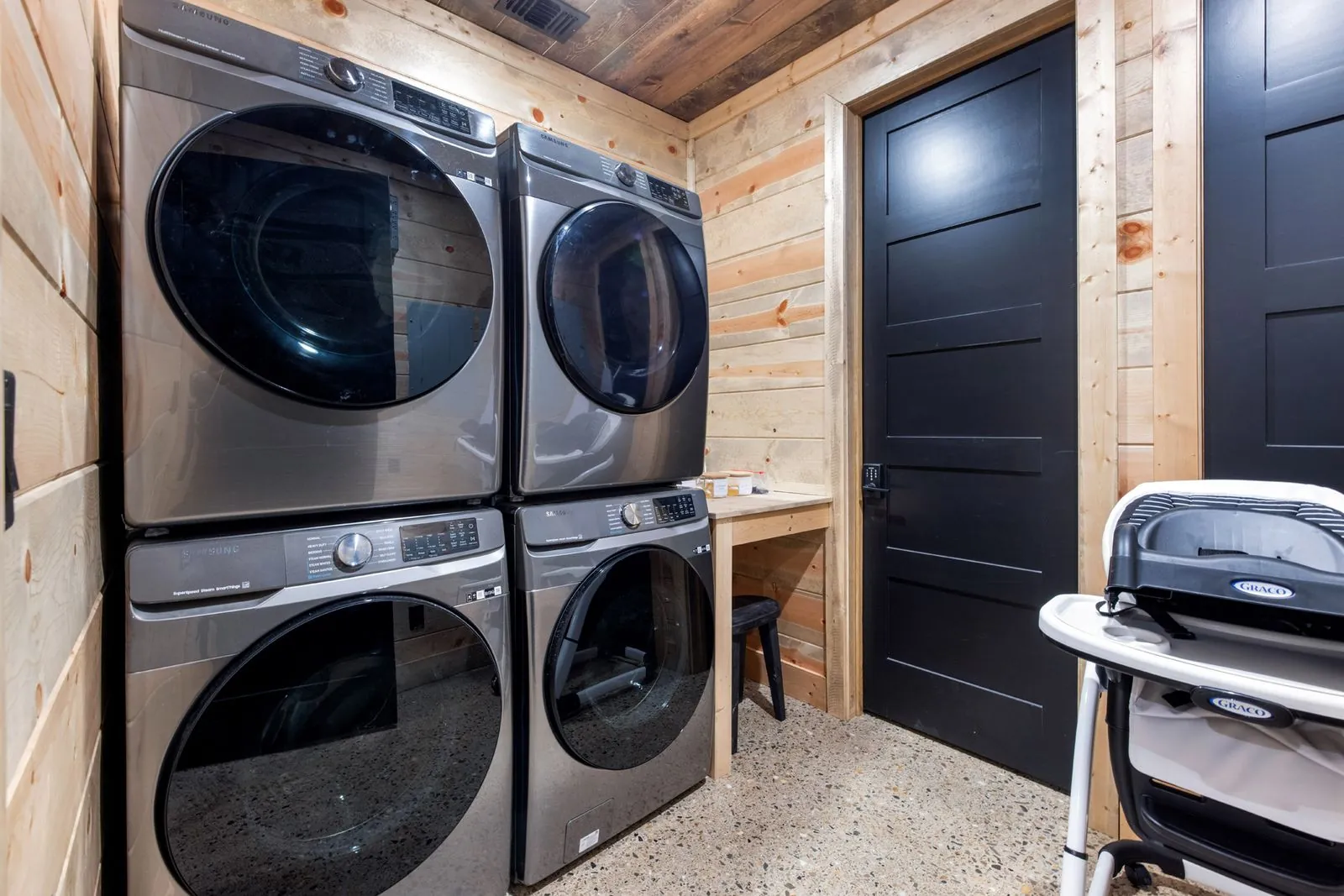 Full laundry room at LivNLove with dual washer and dryer sets, dark cabinetry, and storage space