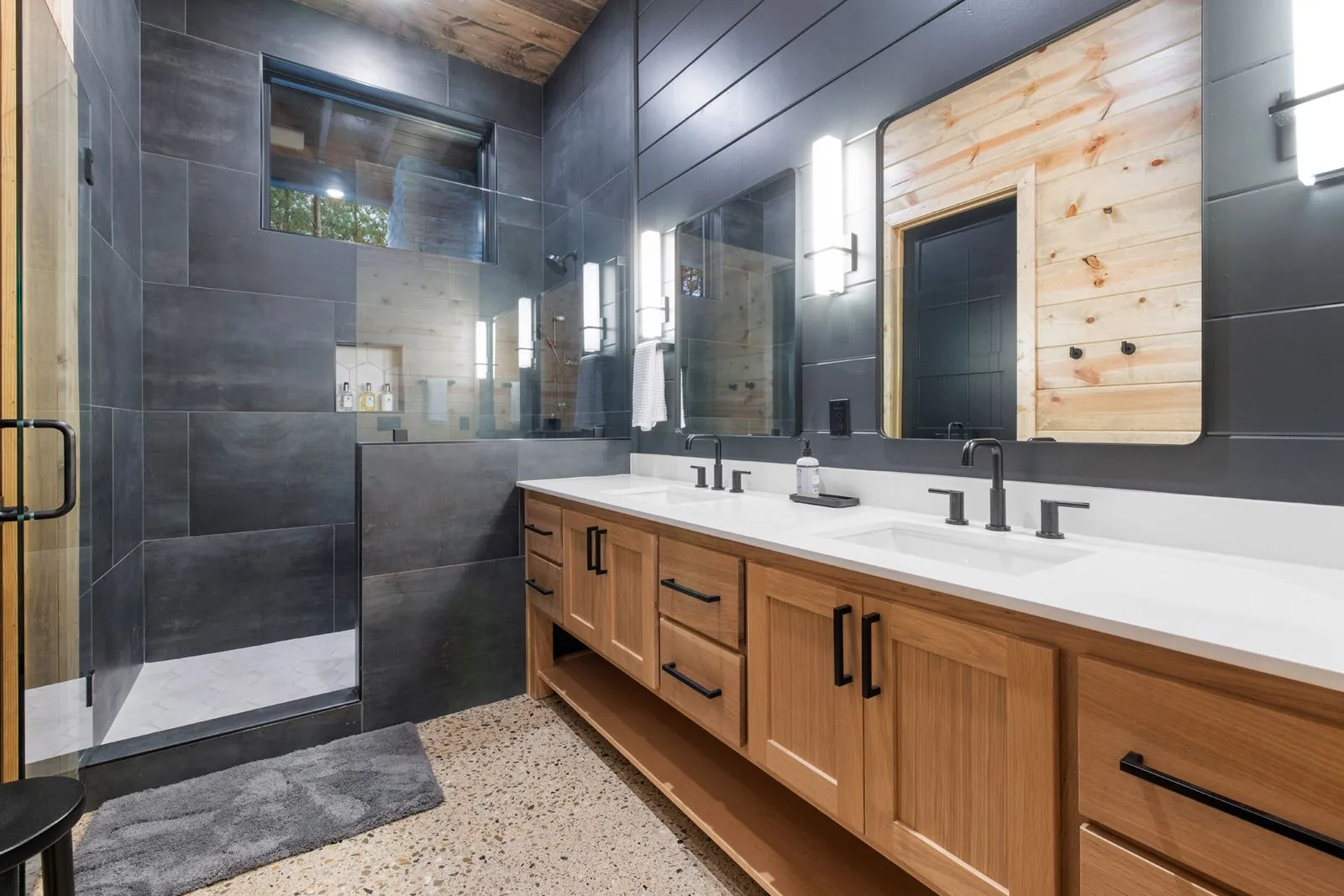 Soaking jetted tub with bath caddy in charcoal-tiled and wood-paneled bathroom at LivNLove