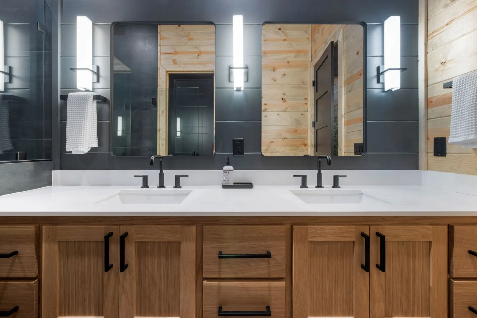 Walk-in shower with dark tile surround, dual rain showerhead, and hexagonal niche detail at LivNLove