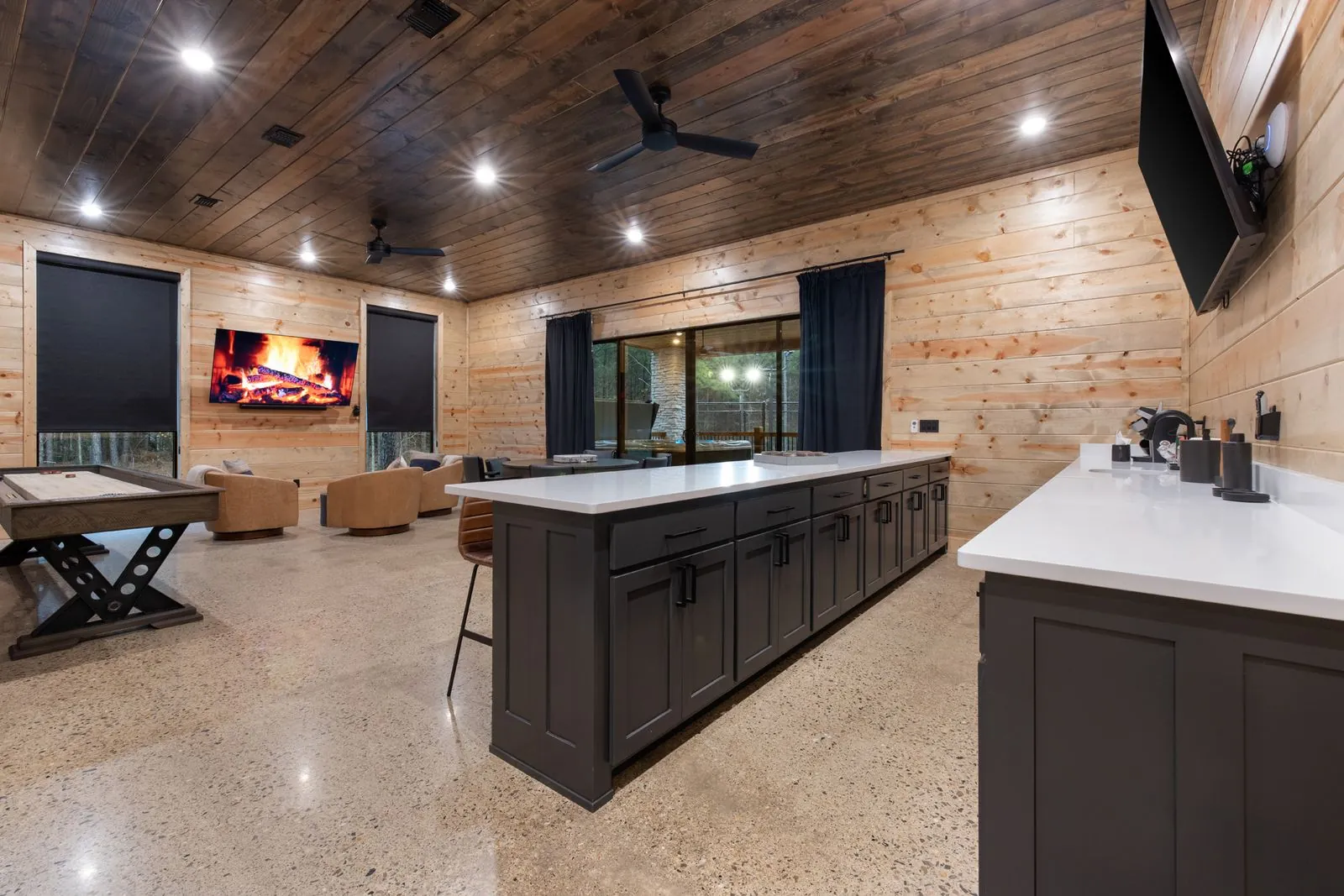 Upper-level kitchenette at LivNLove with dark island, white countertop, pendant lights, and wood cathedral ceiling