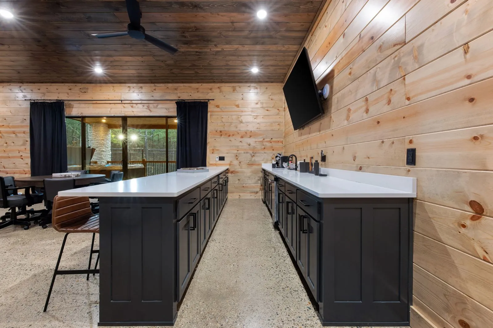Upper kitchen area at LivNLove with dark island, white counter, fireplace, and polished concrete floors