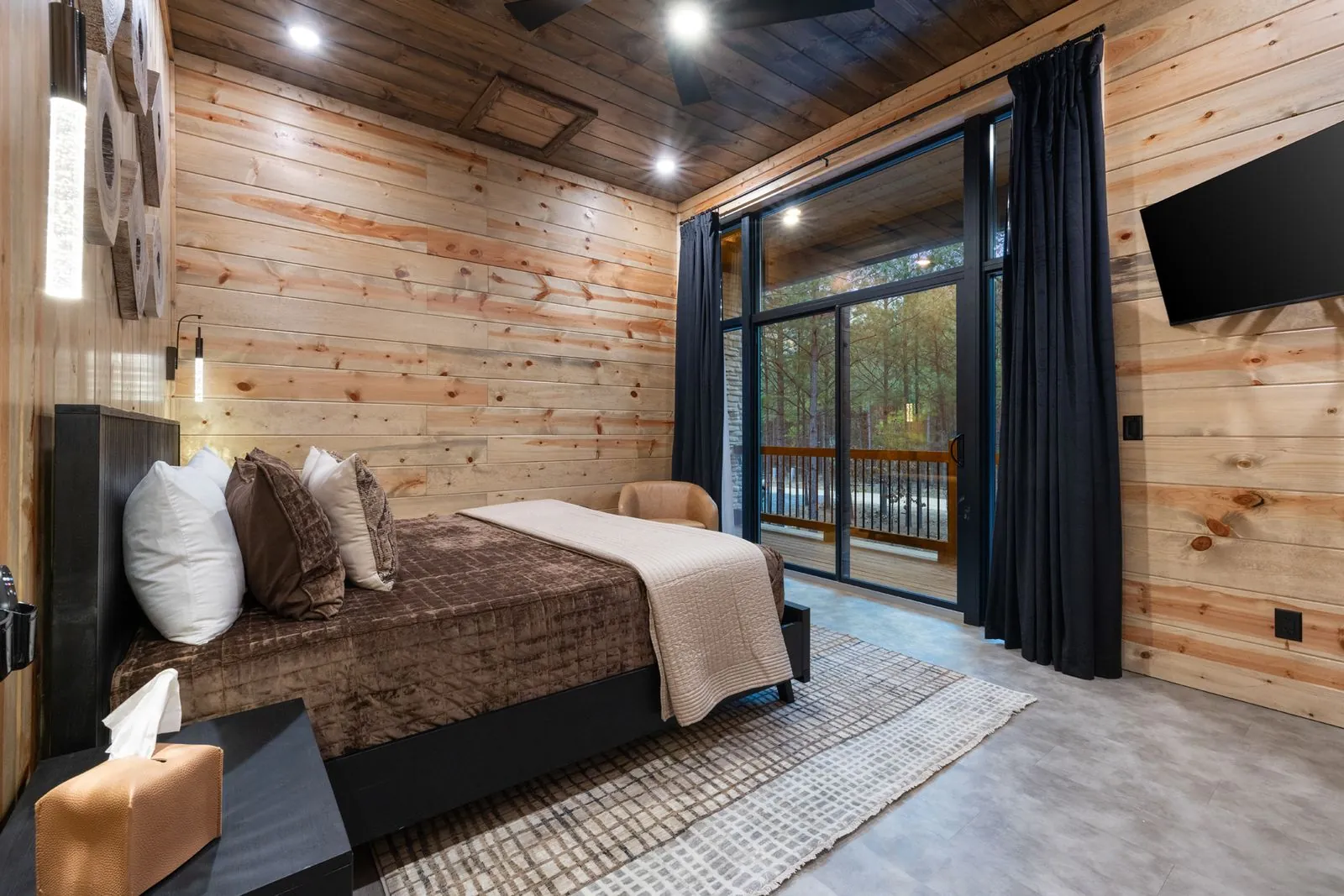 King bed close-up at LivNLove showing textured white coverlet, blue accent pillows, and wood headboard wall with art