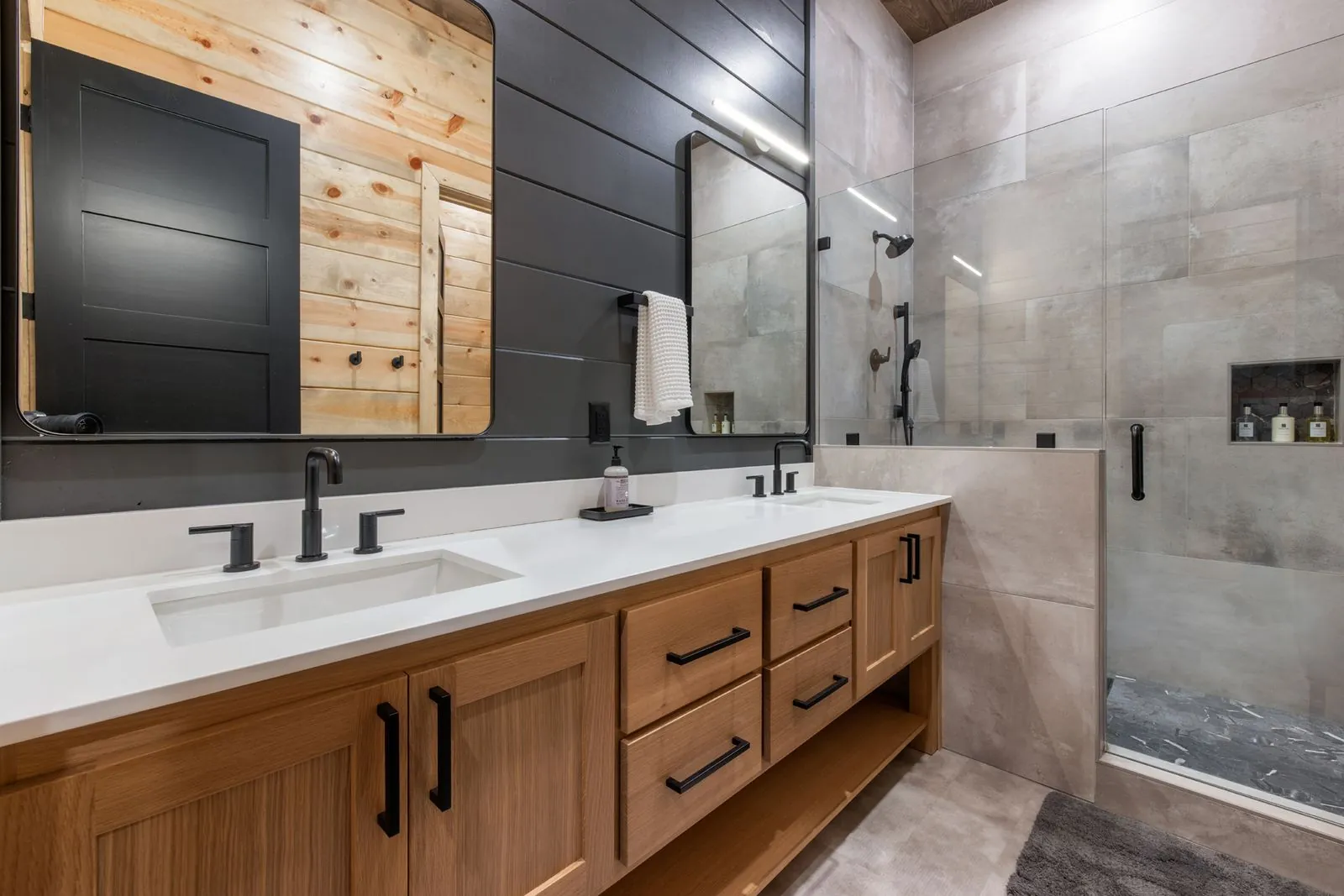 Double vanity bathroom at LivNLove with two mirrors, wood cabinets, dark backsplash, and polished concrete floor