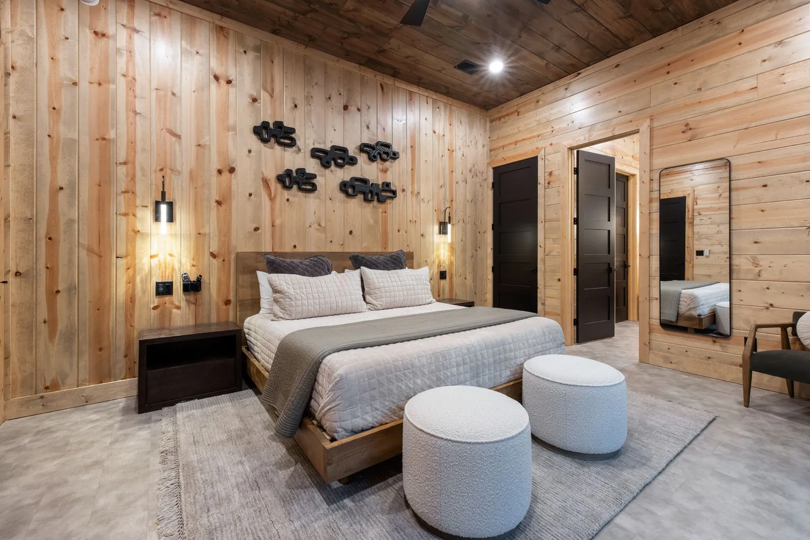 Bedroom at LivNLove with metal-frame king bed, wood mushroom art accent wall, and warm ambient sconce lighting