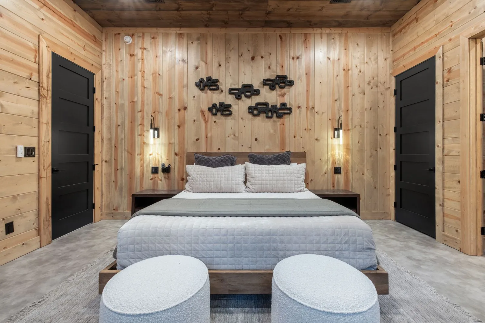 Close-up of king bed at LivNLove with white textured bedding, decorative wood mushroom wall sculptures, and sconce