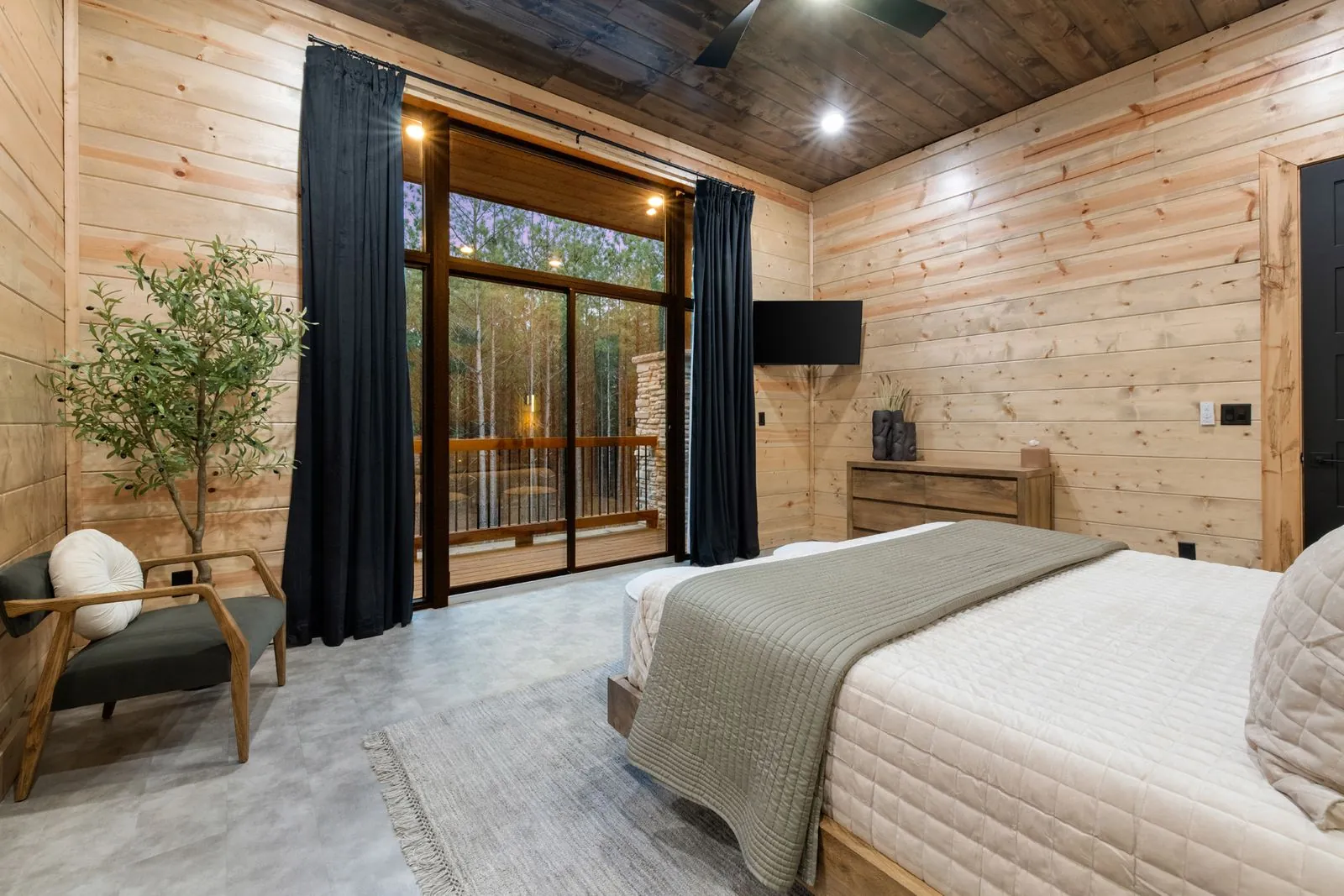Bedroom at LivNLove with woven circular wall art above king bed, blue accent bedding, and bedside pouf