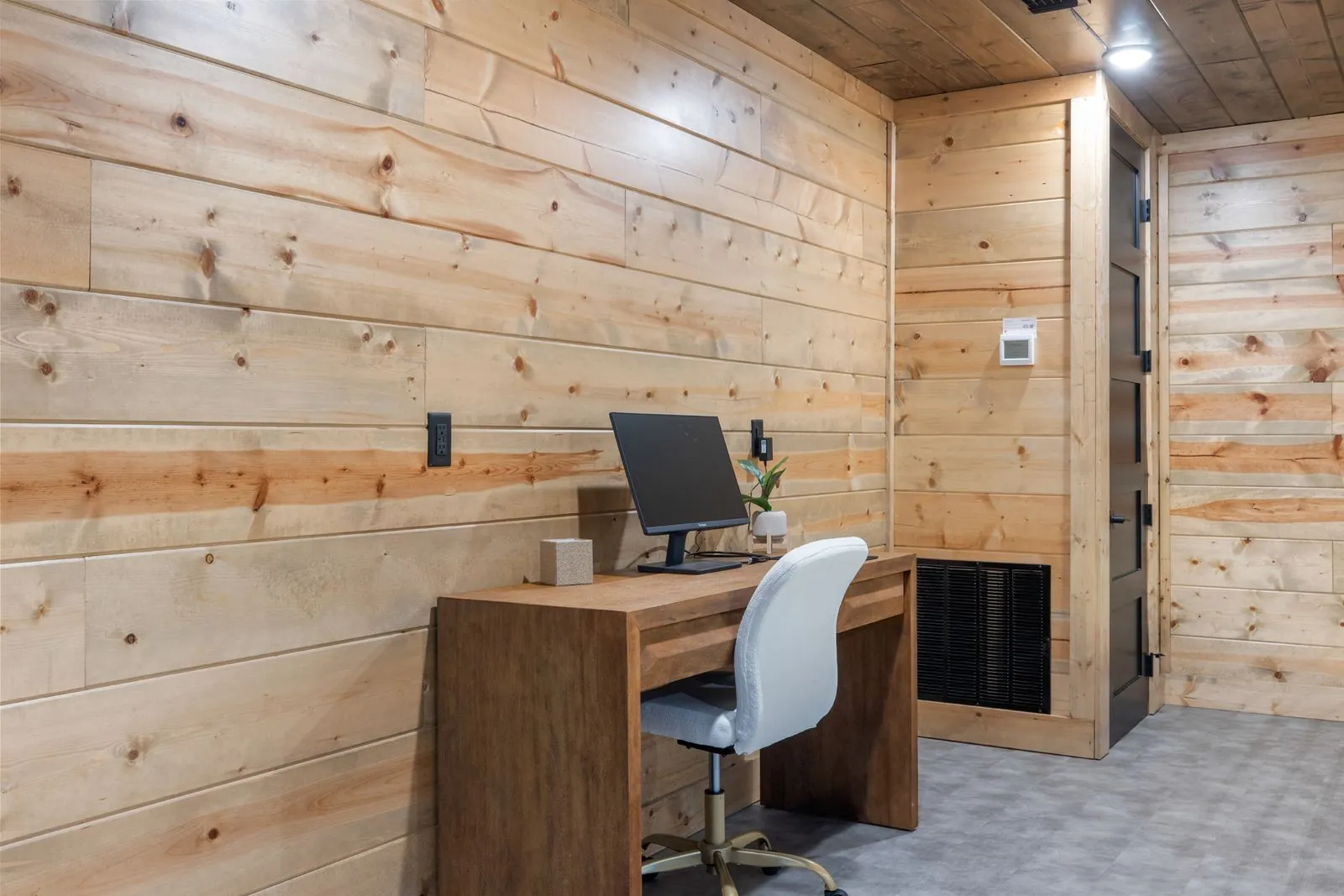 Dedicated work desk area at LivNLove with wooden desk, white chair, monitor, and wood-paneled walls
