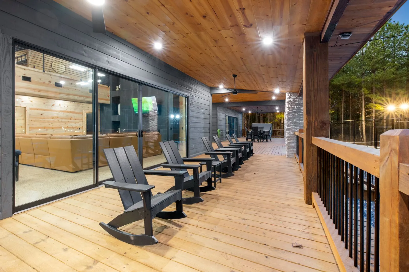 Covered outdoor patio at LivNLove with Adirondack chairs, stone accent walls, and ceiling-mounted TV