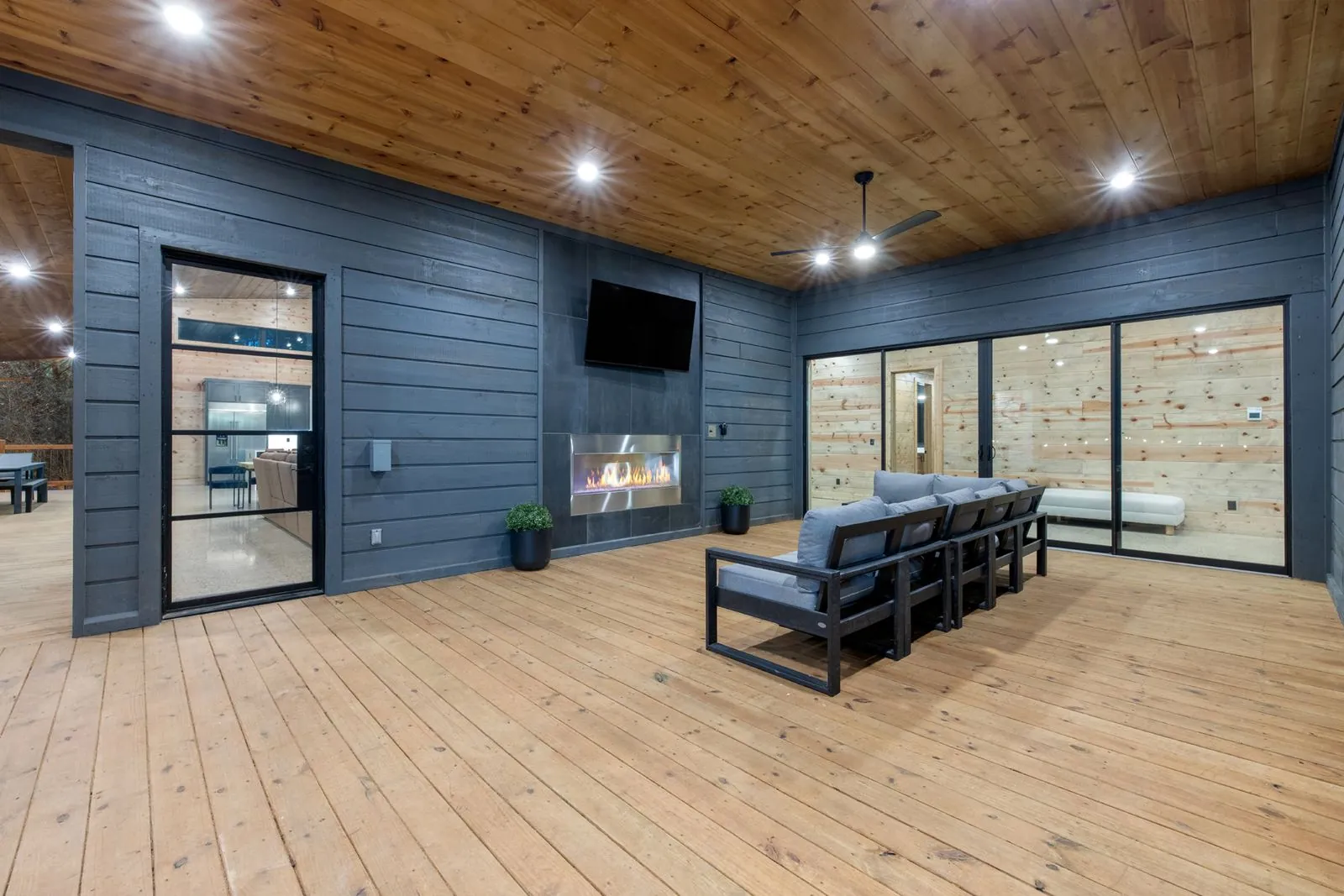 Covered outdoor deck at LivNLove with dark gray lounge furniture and views of the surrounding forest