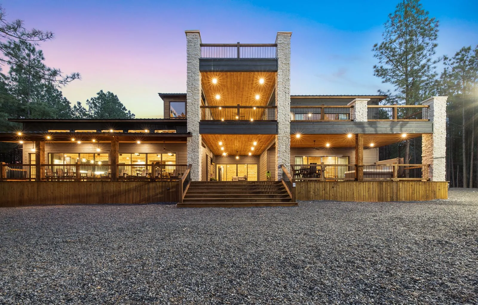 LivNLove large group cabin in Broken Bow for 22 guests — multi-level decks and warm exterior lighting at dusk