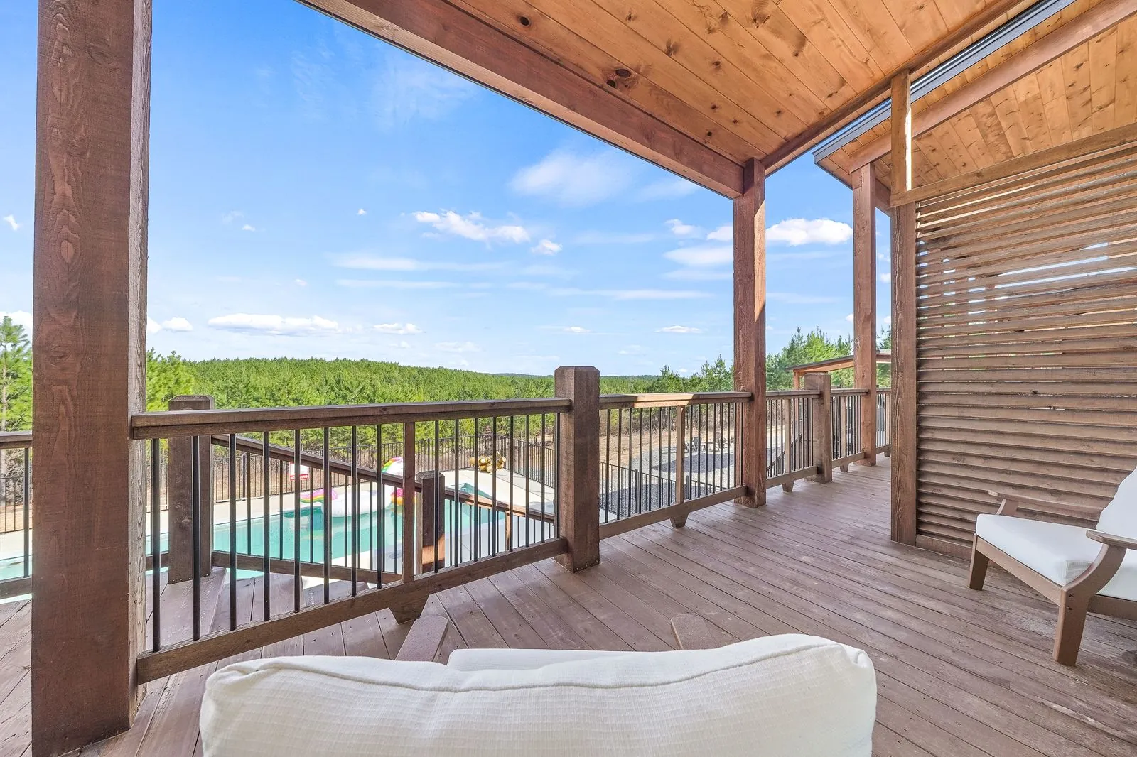 Covered balcony at The Malibu surrounded by pine trees with wood ceiling and iron railing