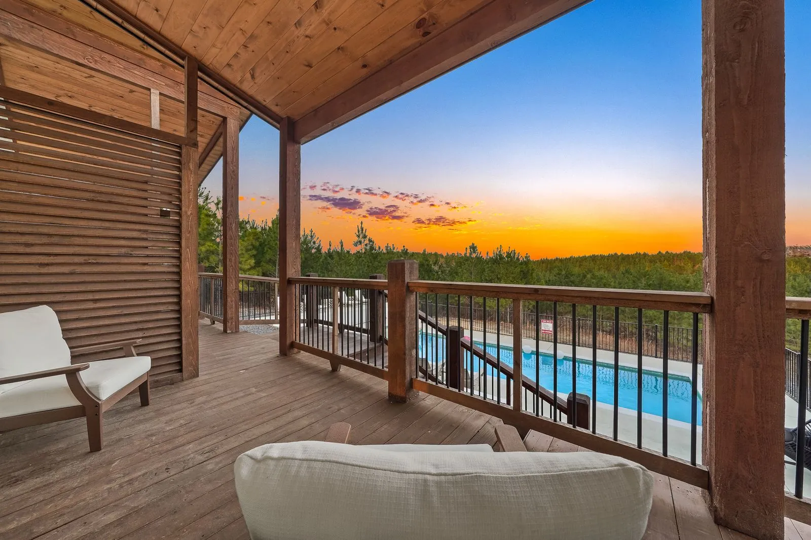 Bedroom at The Malibu with vaulted wood ceiling, king bed, gray bedding, ceiling fan, and sunset balcony view