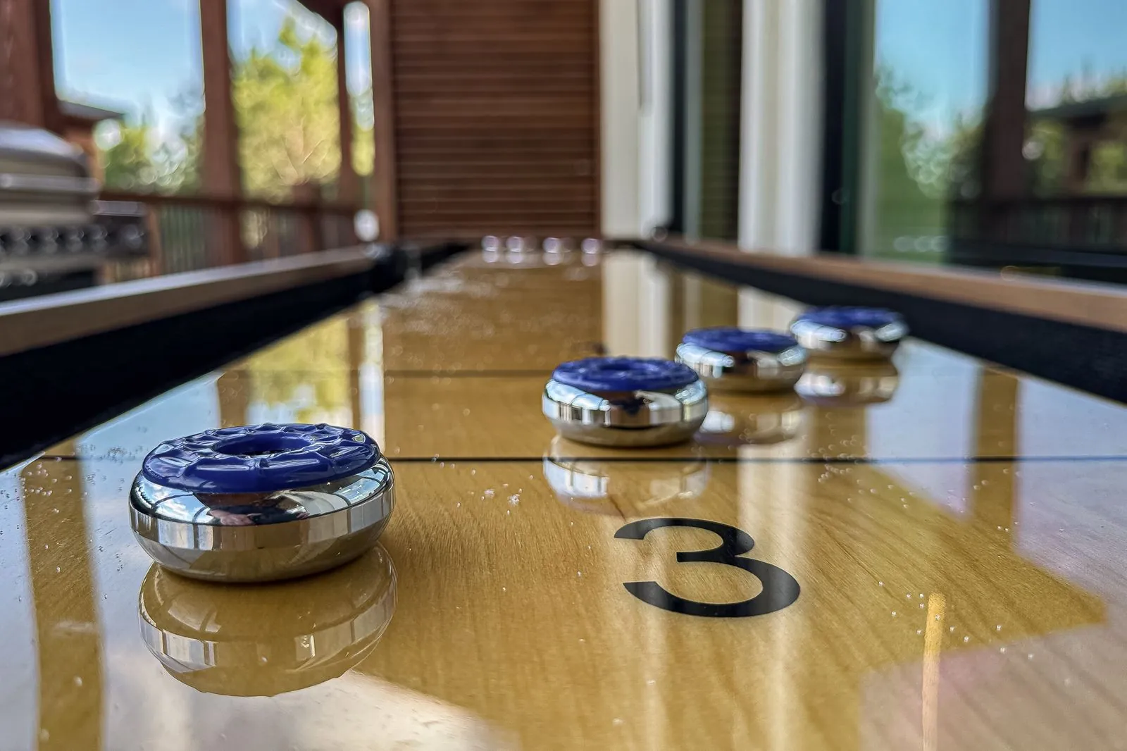 Shuffleboard table close-up at The Malibu game area with polished wood surface and numbered pucks