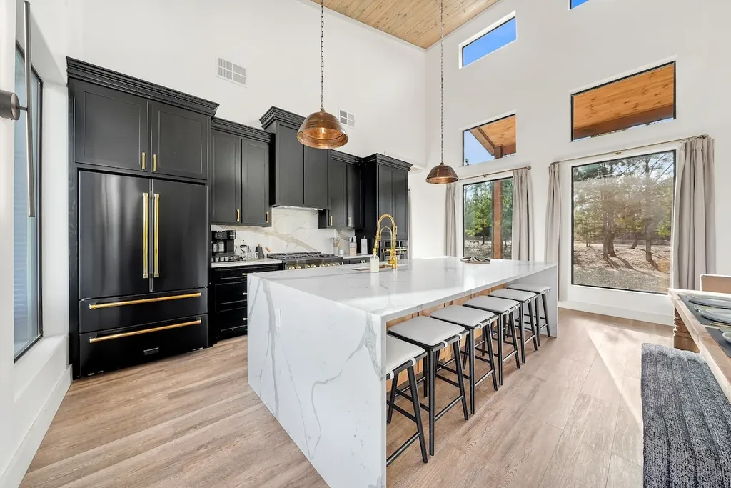 Marble waterfall island with counter stools and black cabinetry