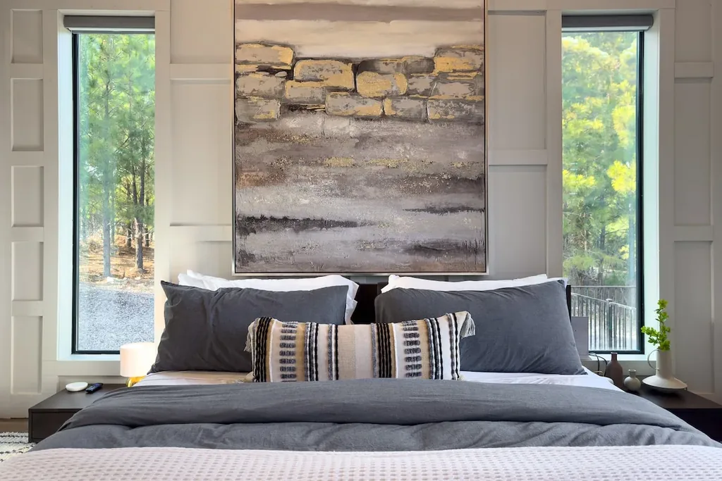 King bed and stone artwork between floor-to-ceiling windows