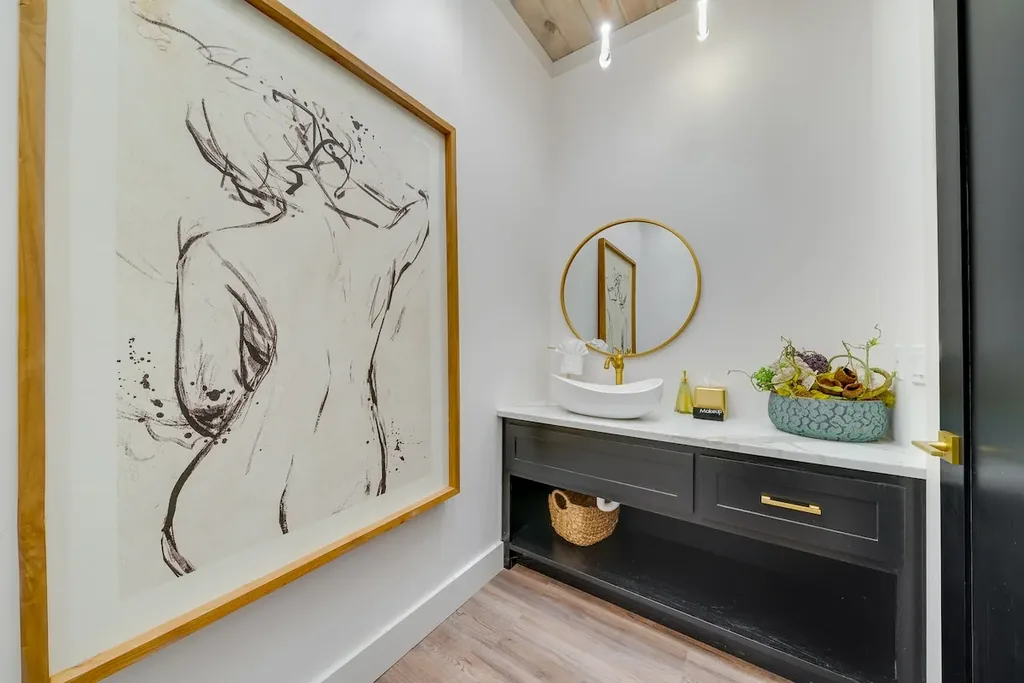 Half bathroom vanity with black cabinetry and gold mirror
