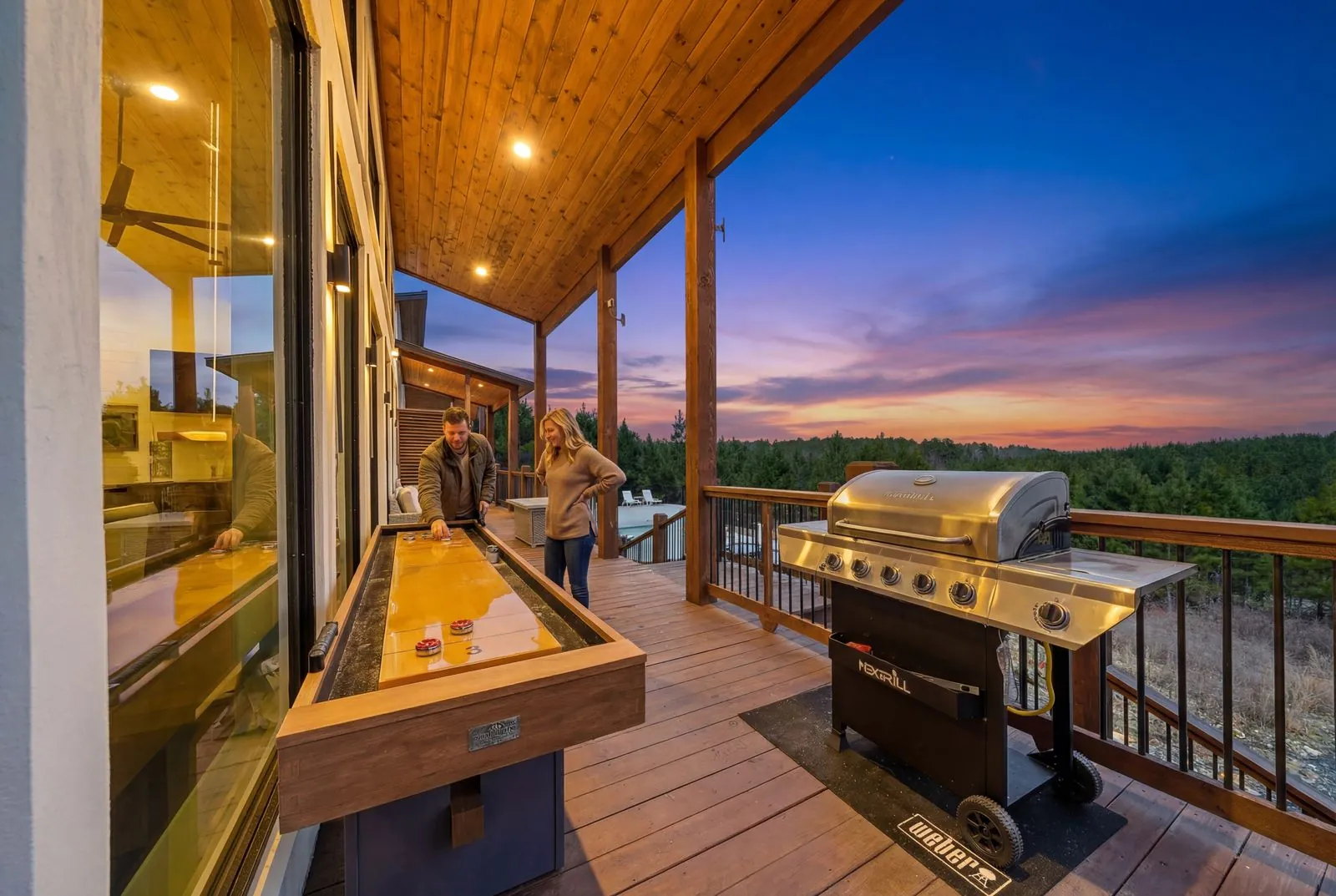 Outdoor grilling station on the covered deck at The Malibu with stainless steel BBQ and sunset sky