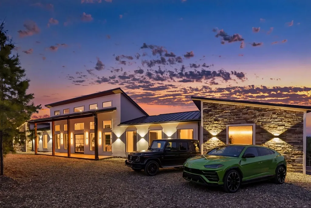 Front exterior of The Malibu modern farmhouse cabin at dusk with stone accents and warm interior glow in Broken Bow