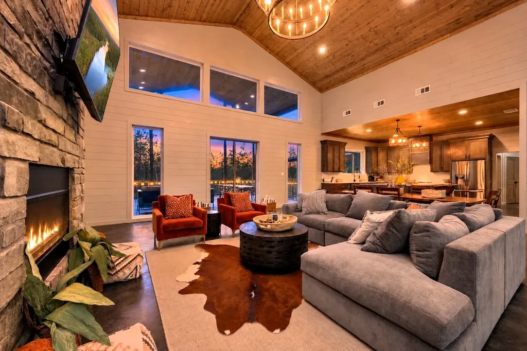Miko Chukka — Gather around the stone fireplace in this open living room, where a wall of glass doors frames the sunset and the deck beyond.