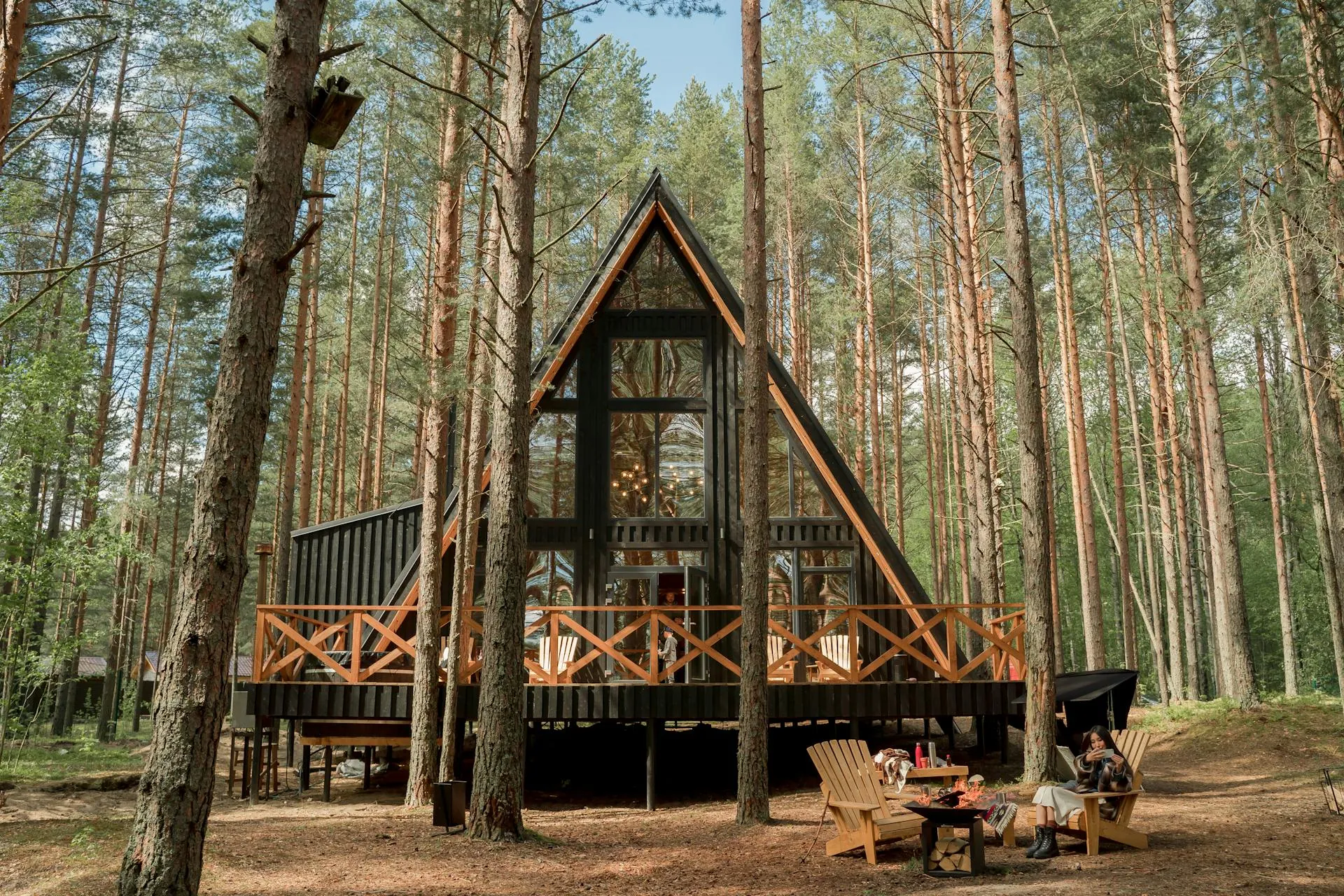 A-frame cabin with deck surrounded by tall pine trees in a forest setting
